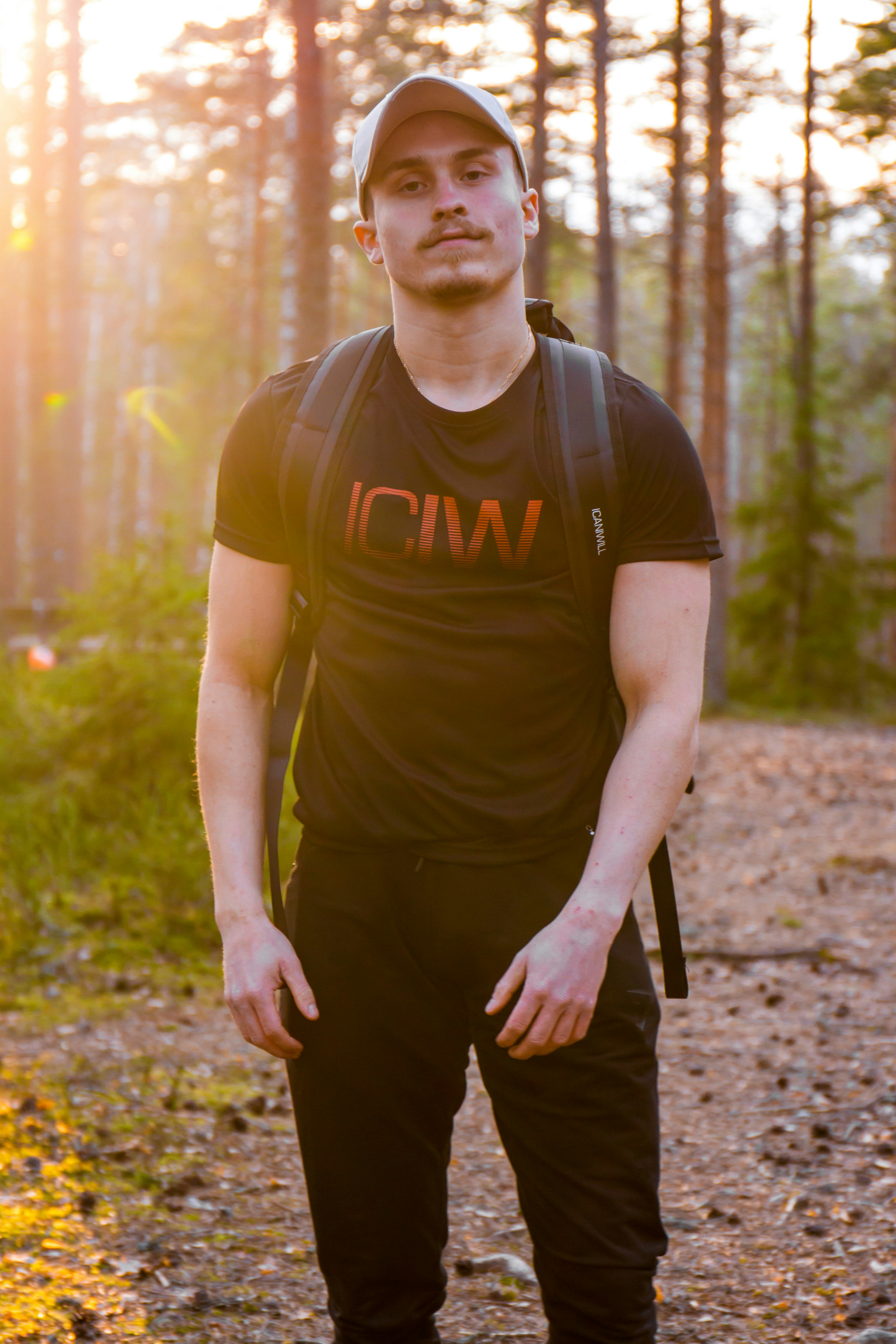 man in brown crew neck t-shirt and black pants standing on forest during daytime